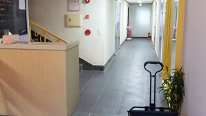 A hotel corridor with a reception desk, a staircase, and a luggage trolley. - Busan Inn (Busan)