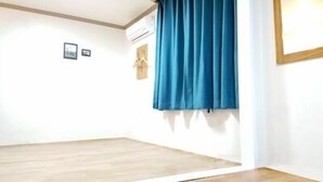 A room with a wooden floor, a blue curtain, and a mirror on the wall. - Busan Inn (Busan)