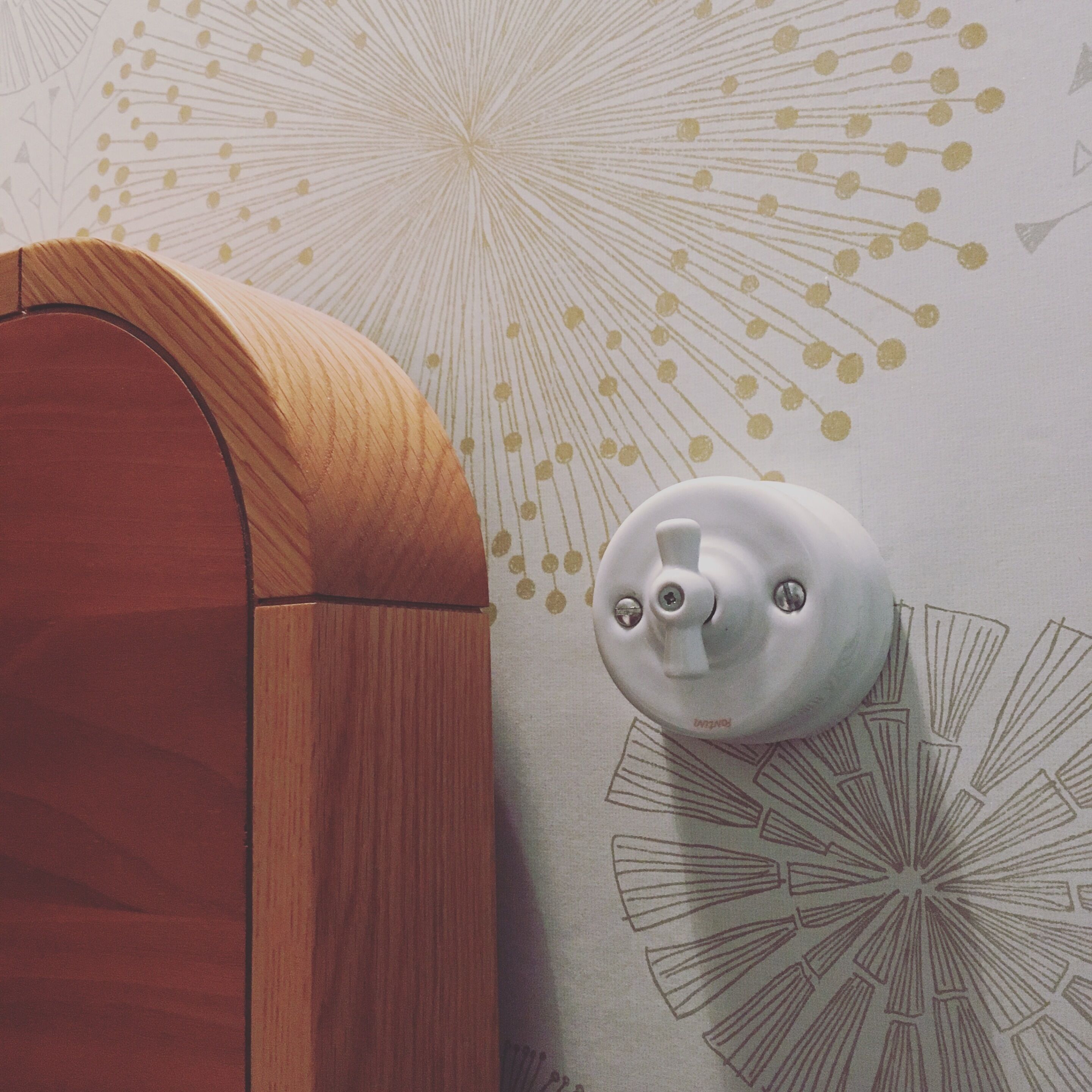 A corner of a room with a wooden door and a wall-mounted light fixture.