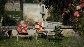 Un jardín con dos sillas y un banco, rodeado de follaje y flores.