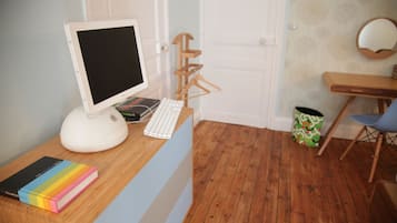Una stanza con una scrivania in legno, un computer, una tastiera, una sedia, una libreria e una porta.