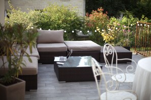 Un espace extérieur aménagé avec un canapé, une table avec un ordinateur portable et une chaise.