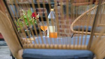 En fletstol med pude, en flaske og et glas med drik på et bord.