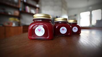 Three jars of red jam with gold lids on a wooden table.