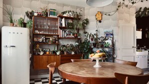 A kitchen with a checkered floor, a white refrigerator, wooden cabinets, and various plants. - Chez Ric et Fer (Coucy-le-Chateau-Auffrique)
