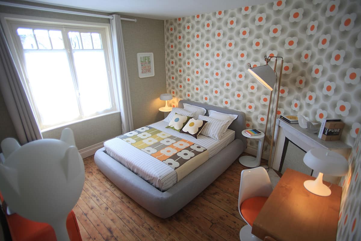 A bedroom with a bed, bedside tables, a chair, a desk, a lamp, and a window.