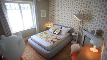 A bedroom with a bed, bedside tables, a chair, a desk, a lamp, and a window.