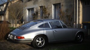 A vintage silver car parked in front of a stone building with multiple windows and a door. - Chez Ric et Fer (Coucy-le-Chateau-Auffrique)