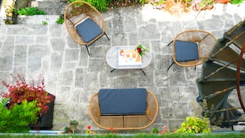 A patio with wicker furniture, a table, and potted plants.
