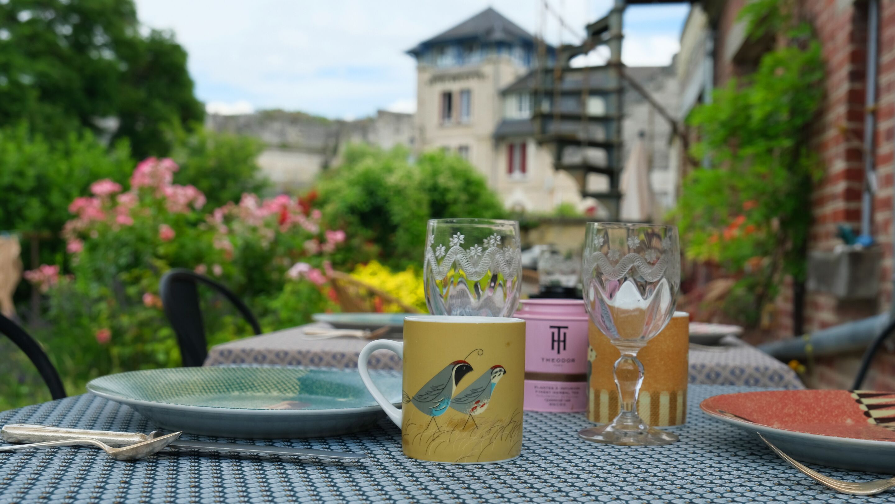 Une table dressée à l’extérieur, avec une tasse, un verre et une assiette.