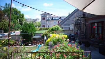 A garden with a metal fence, a blue chair, and a building with a red roof in the background.