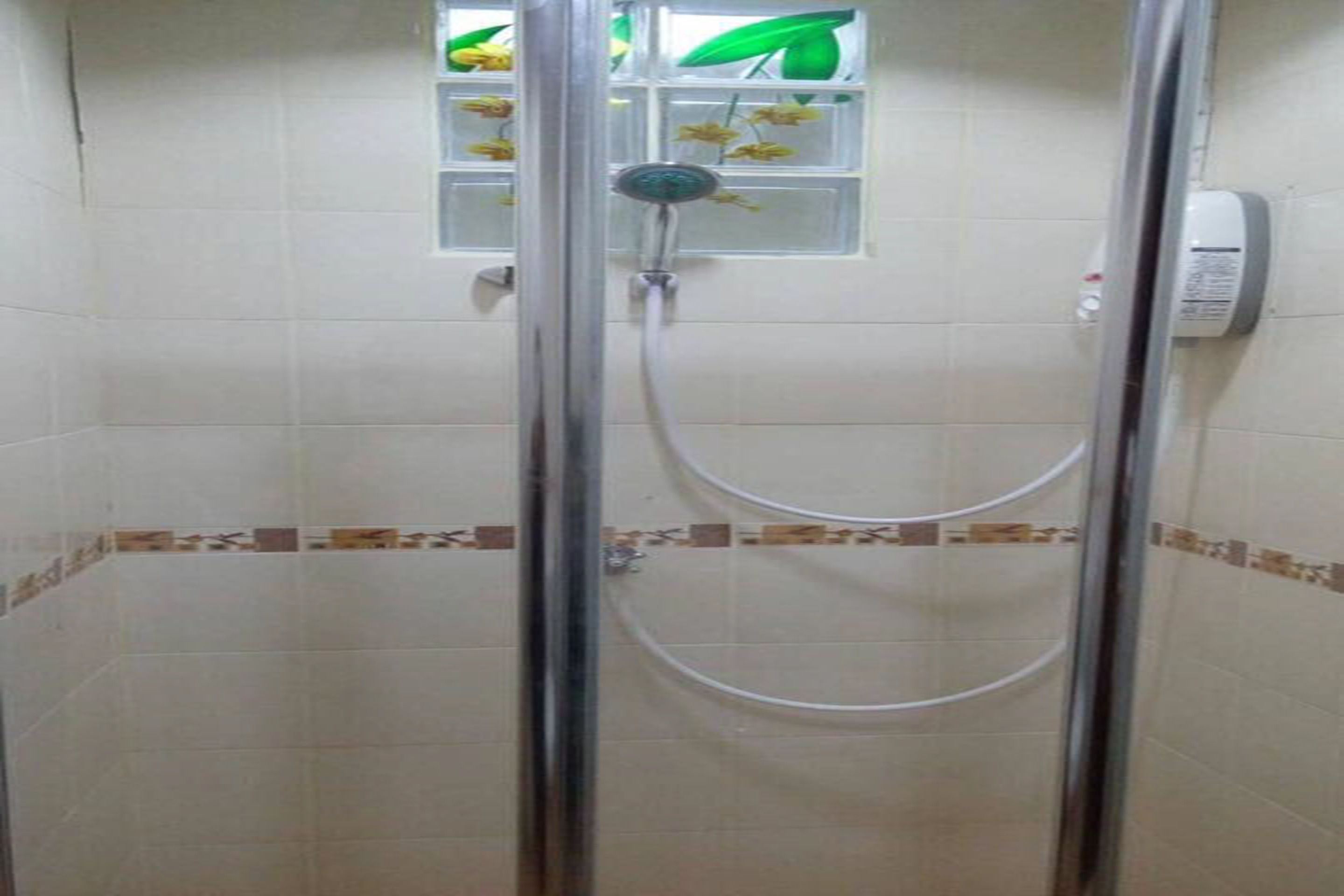 A shower with a glass door, a handheld showerhead, and a wall-mounted control panel.