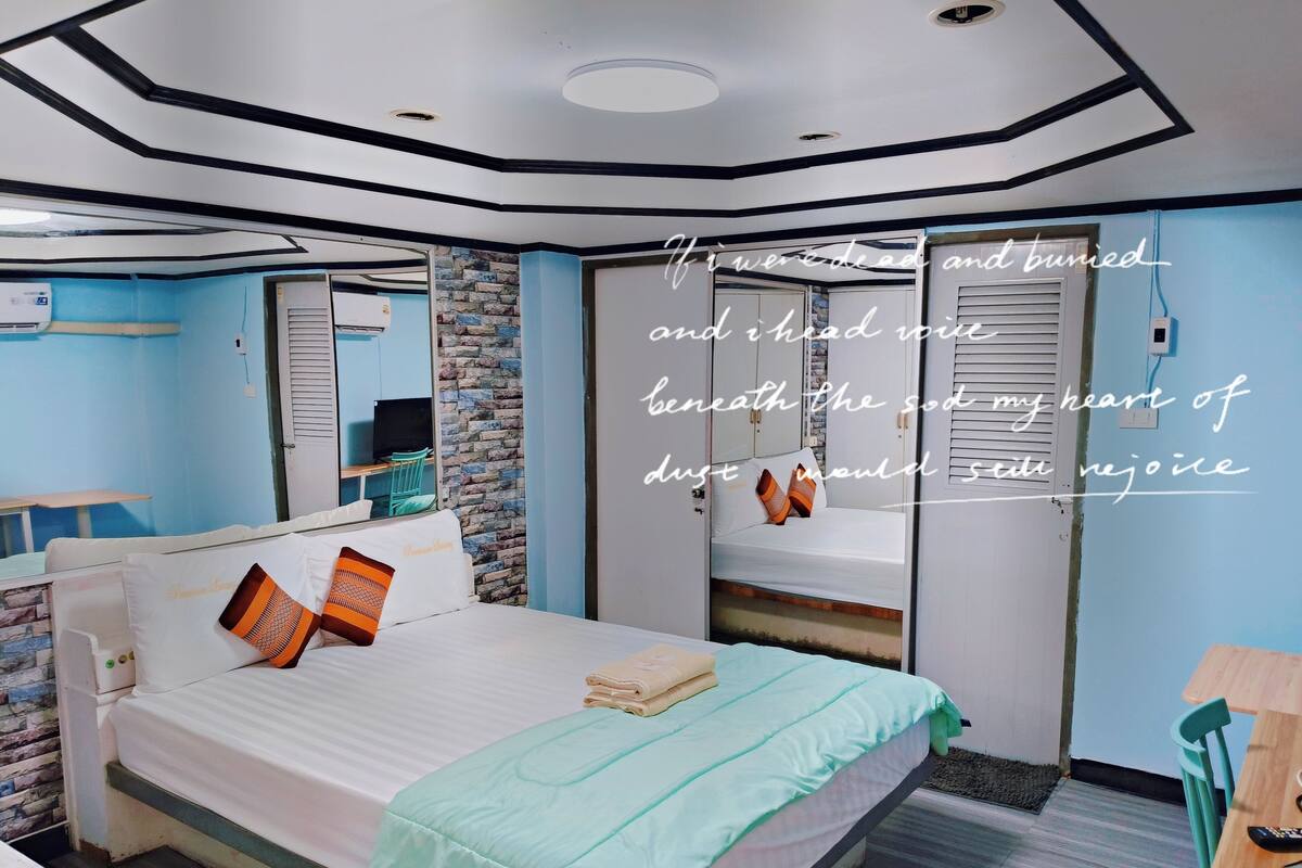A modern bedroom with a bed, bedside table, and a mirror.