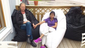 Two people sitting on bean bags on a wooden deck with a wooden fence in the background. - Norrskedika hotell - Gamla Järnhandeln (Osthammar)