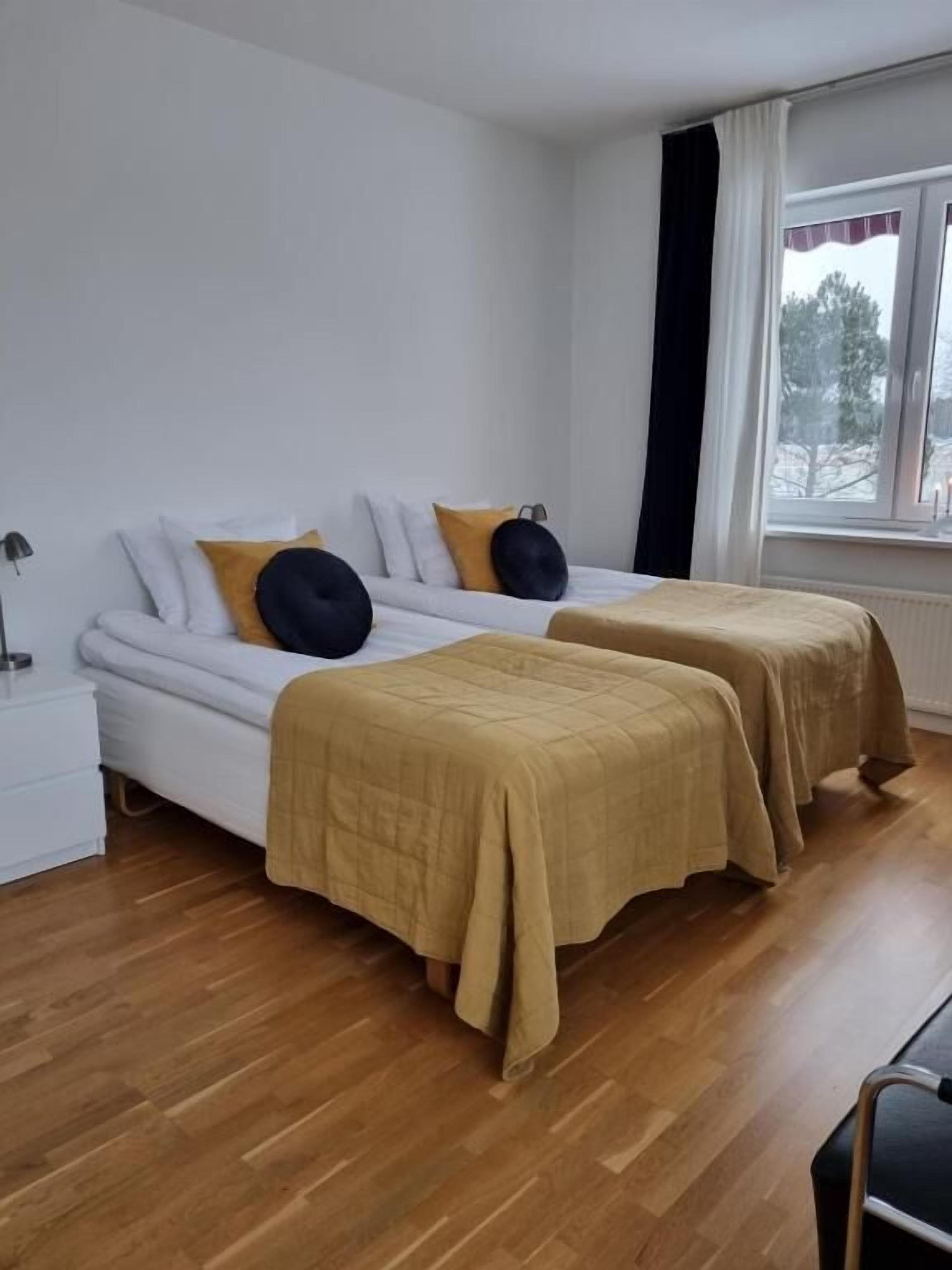 A room with two beds, a window, and a nightstand.