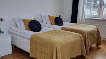 A room with two beds, a window, and a nightstand.