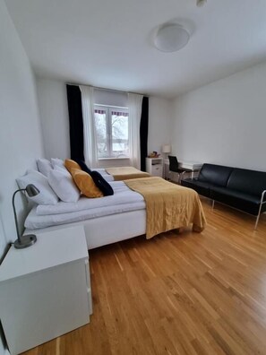 A bedroom with a bed, bedside table, lamp, and a window with curtains. - Norrskedika hotell - Gamla Järnhandeln (Osthammar)