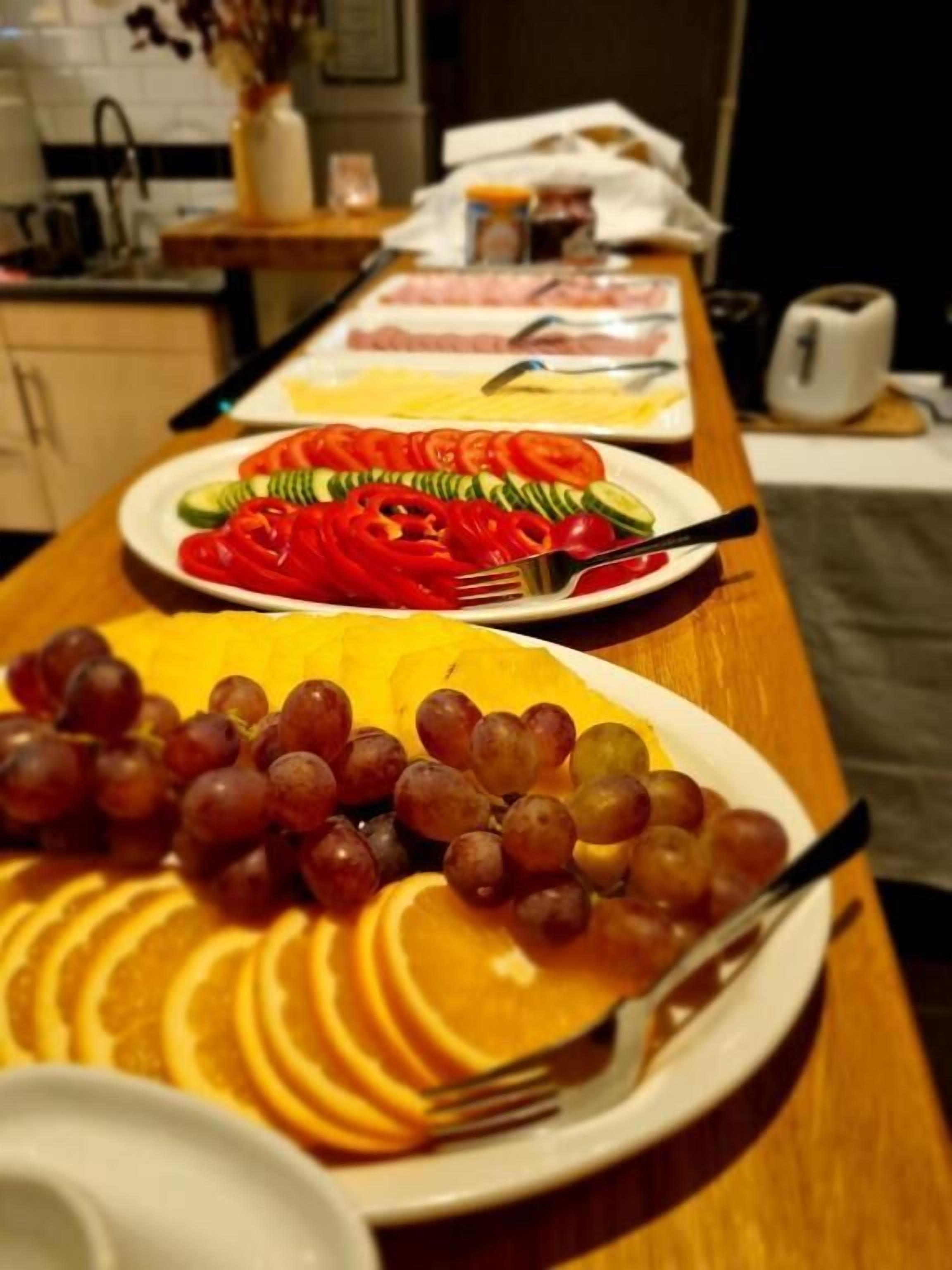 A dining table with plates of sliced fruits and vegetables.