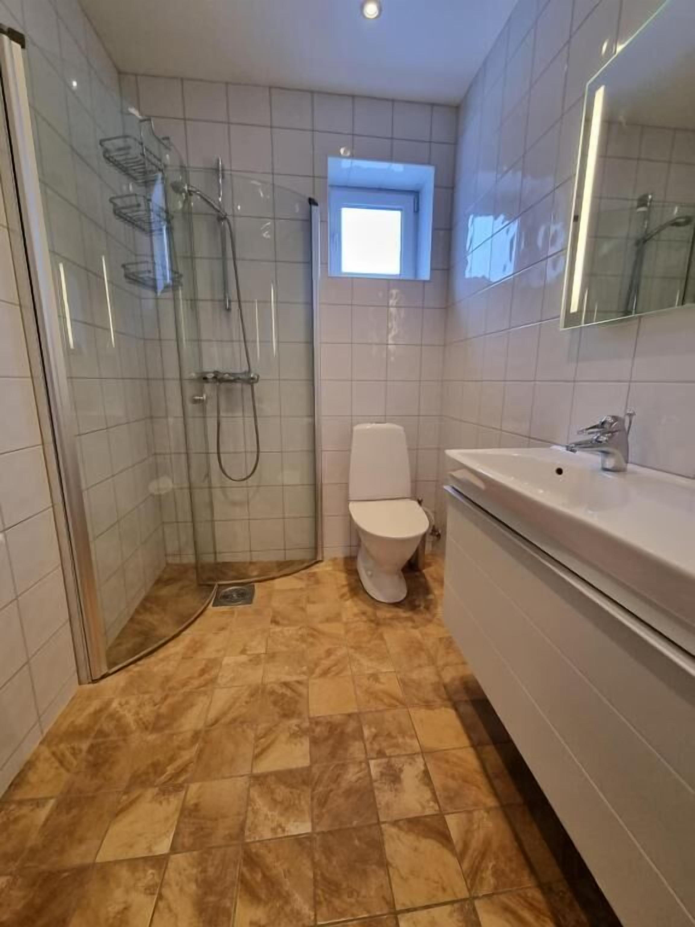 Un baño con ducha acristalada, inodoro y lavamanos.