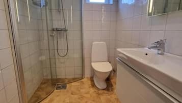 Un baño con ducha acristalada, inodoro y lavamanos.