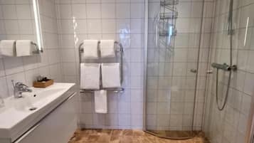 Ett badrum med handfat, spegel, toalett och dusch.