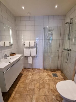 Un baño con lavamanos, espejo, inodoro y ducha.