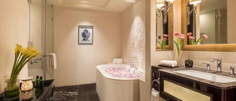 Un baño moderno con bañera, dos lavamanos, un espejo grande y detalles decorativos como flores y un cuadro enmarcado.