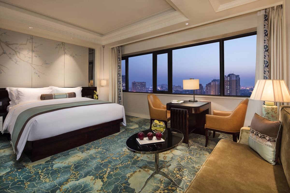 Habitación de hotel con una cama grande, un escritorio, una silla y vistas a la ciudad.