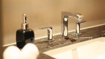 A bathroom with a marble countertop, a sink, and two faucets.