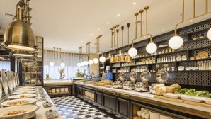 Una cocina moderna con piso a cuadros blancos y negros, electrodomésticos de acero inoxidable y una variedad de vajilla y utensilios a la vista.