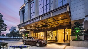 El Hotel Purdy, con un diseño arquitectónico clásico, presenta una entrada imponente y un lujoso coche estacionado al frente.