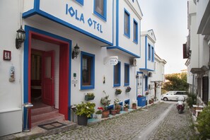 Um edifício branco com detalhes em azul e uma porta vermelha, com a inscrição "IOLA OTEL".