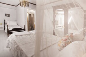 Quarto com duas camas, uma cama com dossel e vista para o banheiro.