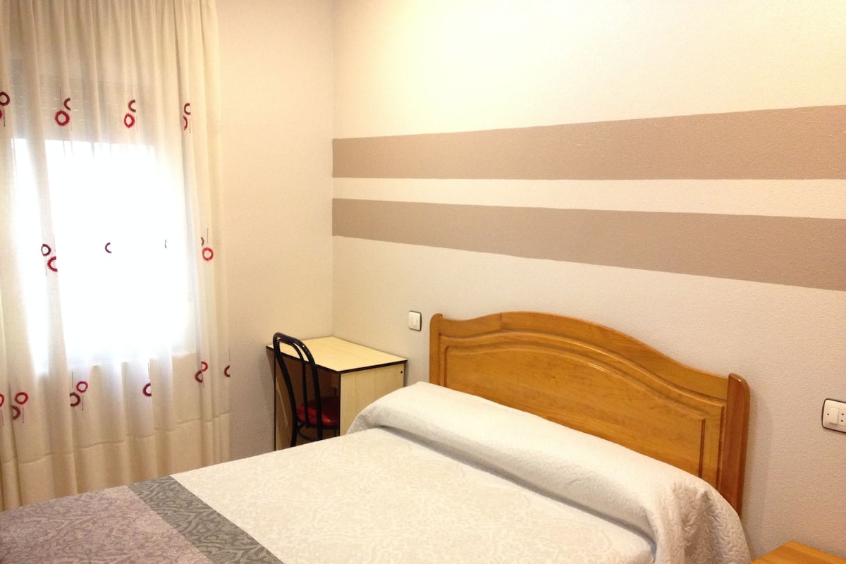 Una habitación de hotel con una cama, un escritorio y una silla.