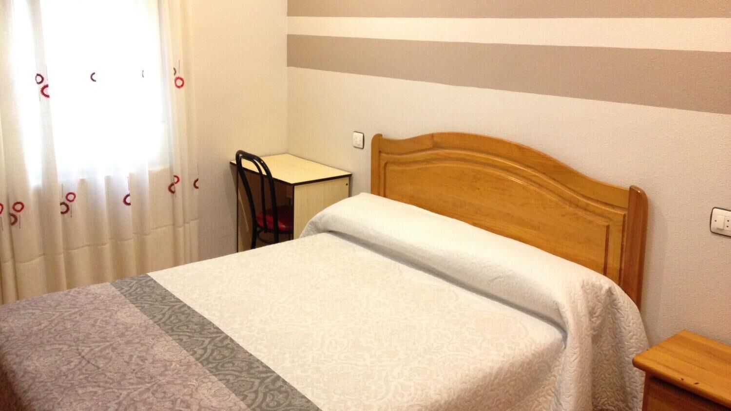 Un dormitorio con una cama, un escritorio y una silla.