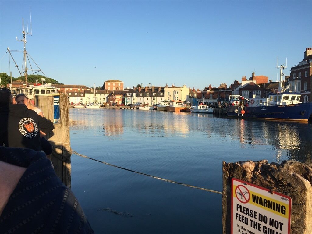 A harbor with boats, a warning sign, and buildings in the background.