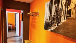 A hallway with a wooden floor, a small table with a lamp, and a wall-mounted light fixture. - Apartments Casa da Enzo (Goslar)
