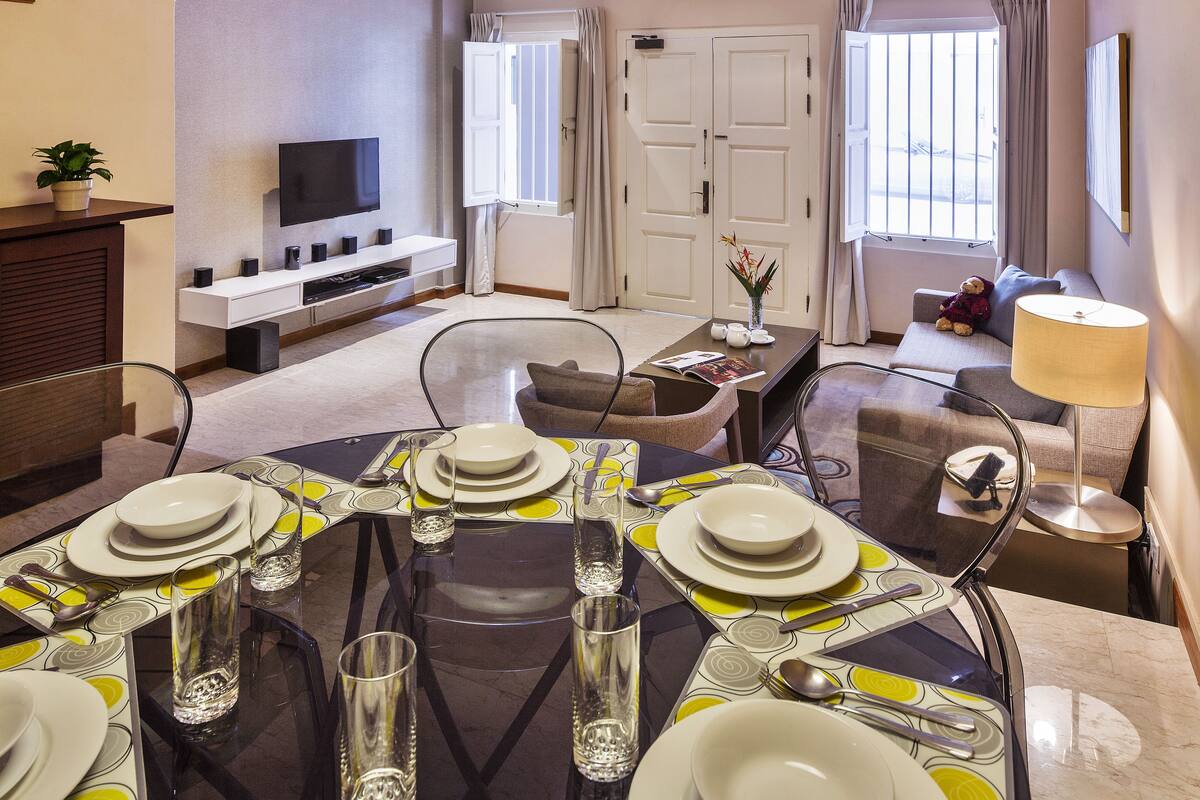 A modern living room with a dining area, a TV, and a staircase.