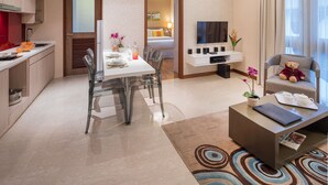 Una moderna camera d'albergo con zona pranzo, angolo salotto e vista sull'esterno.