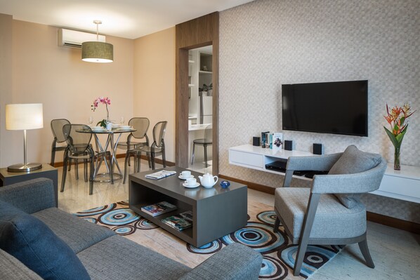 Una sala de estar moderna con sofá, mesa de centro, televisor y comedor.