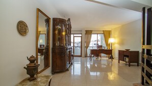 Um quarto amplo com um espelho grande, um armário de madeira, uma escrivaninha e uma mesa.