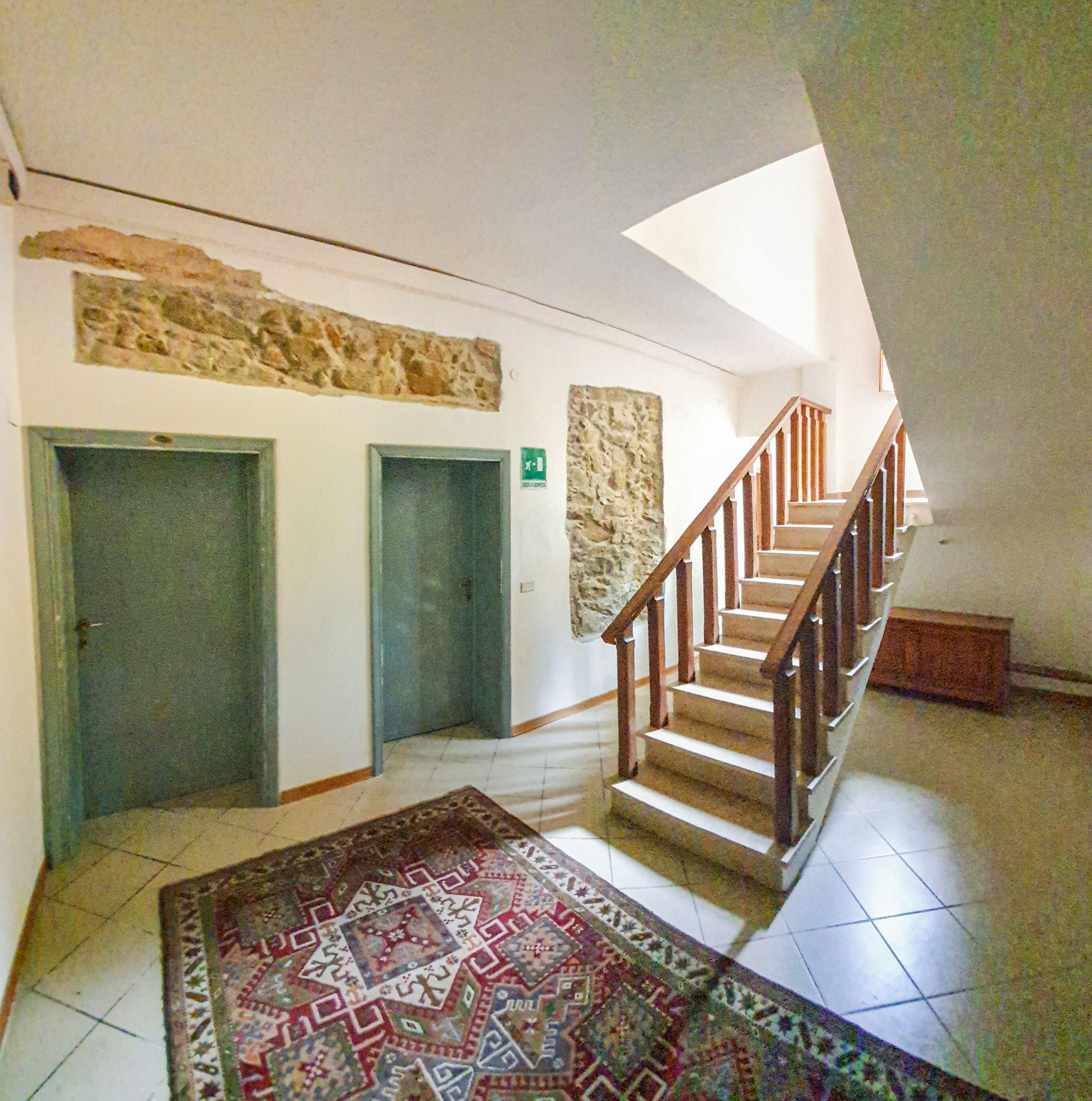 A staircase with wooden railings and a patterned rug on the floor.