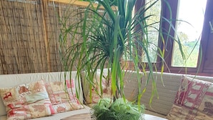 A round wooden table with a moss-like centerpiece, surrounded by a cushioned sofa with patterned cushions. - Albergo Bellavista (Lamporecchio)