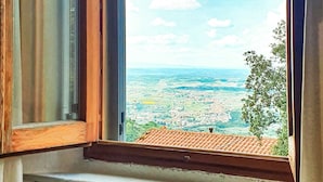 A window with a stone ledge and a view of a distant landscape. - Albergo Bellavista (Lamporecchio)