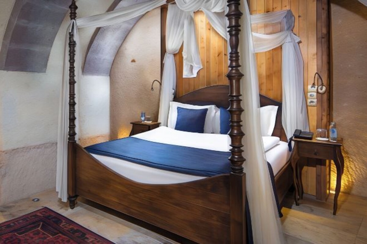 A four-poster bed with a canopy, wooden headboard, bedside tables, and a nightstand.