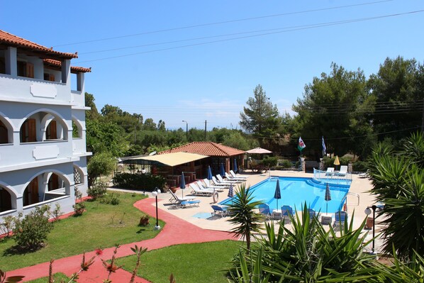 A pool area with lounge chairs, a swimming pool, and a building with arches.