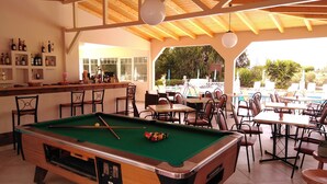 Een biljarttafel in een ruimte met een bar en terras.