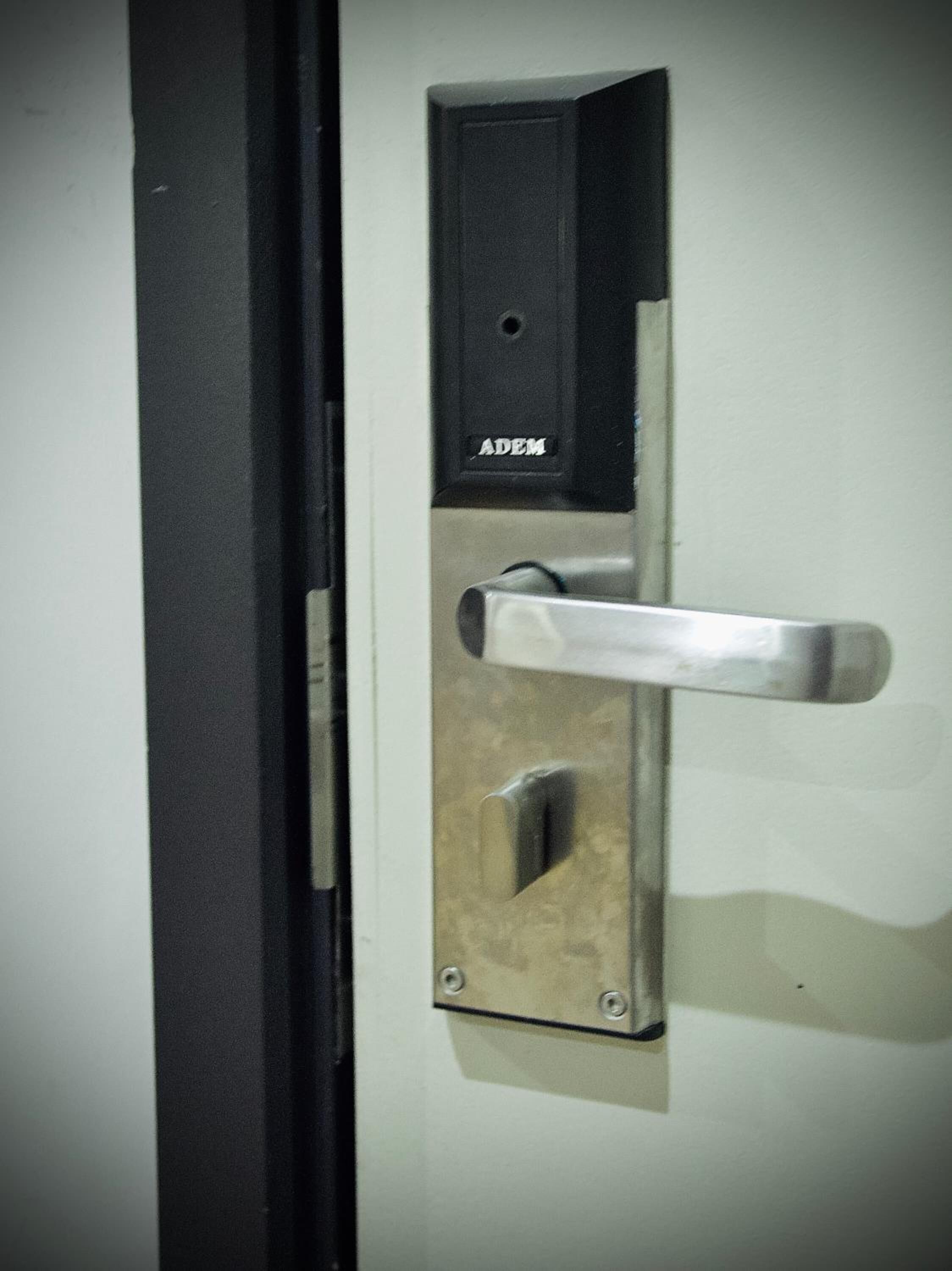 Une porte dotée d’une poignée noire et d’une plaque métallique portant le nom de la marque « ADEM ».