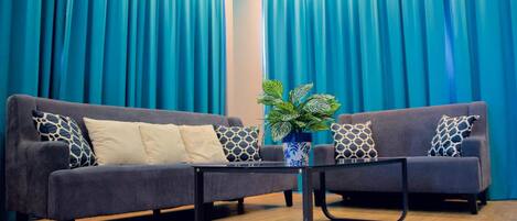 A modern living room with a grey sofa set, a black coffee table, and a potted plant.