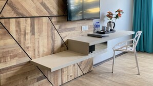 A modern living room with a TV mounted on a wooden wall, a small table with a chair, and a teal curtain. - G5 Hotel & Serviced Apartment (Johor Bahru)